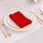 Red napkin neatly folded on an elegant dinner plate with gold trim.
