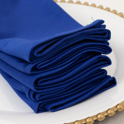 Stack of deep blue fabric napkins neatly folded on a decorative plate.