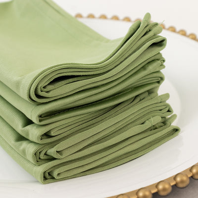 Stack of green cloth napkins neatly folded on a decorative plate.