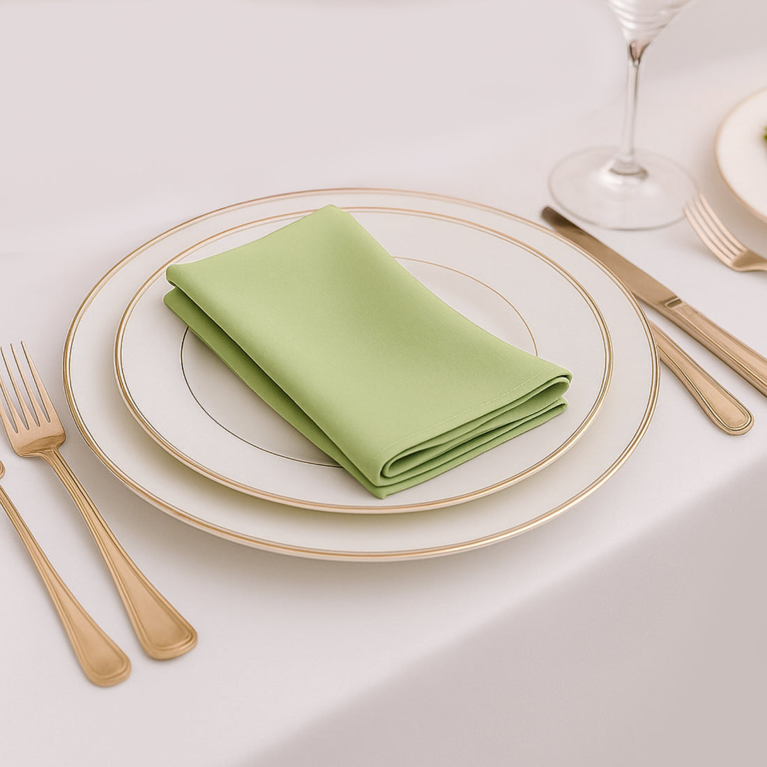 Green napkin elegantly folded on a white plate with gold trim.