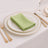 Green napkin elegantly folded on a white plate with gold trim.