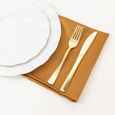 Elegant gold cutlery on a brown napkin with white dinner plates
