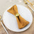 Elegant gold napkin ring on a folded brown napkin atop a white plate.