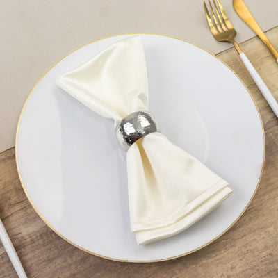 Elegant cream napkin with silver ring on a white plate.