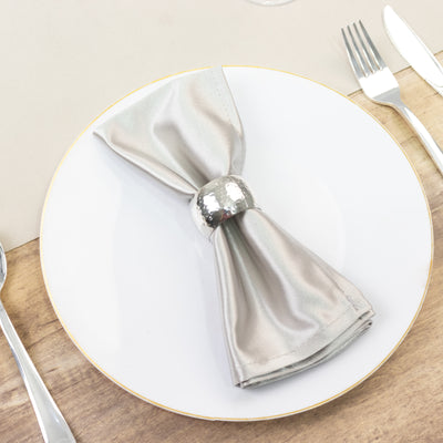 Elegant silver napkin with ring on a white plate.