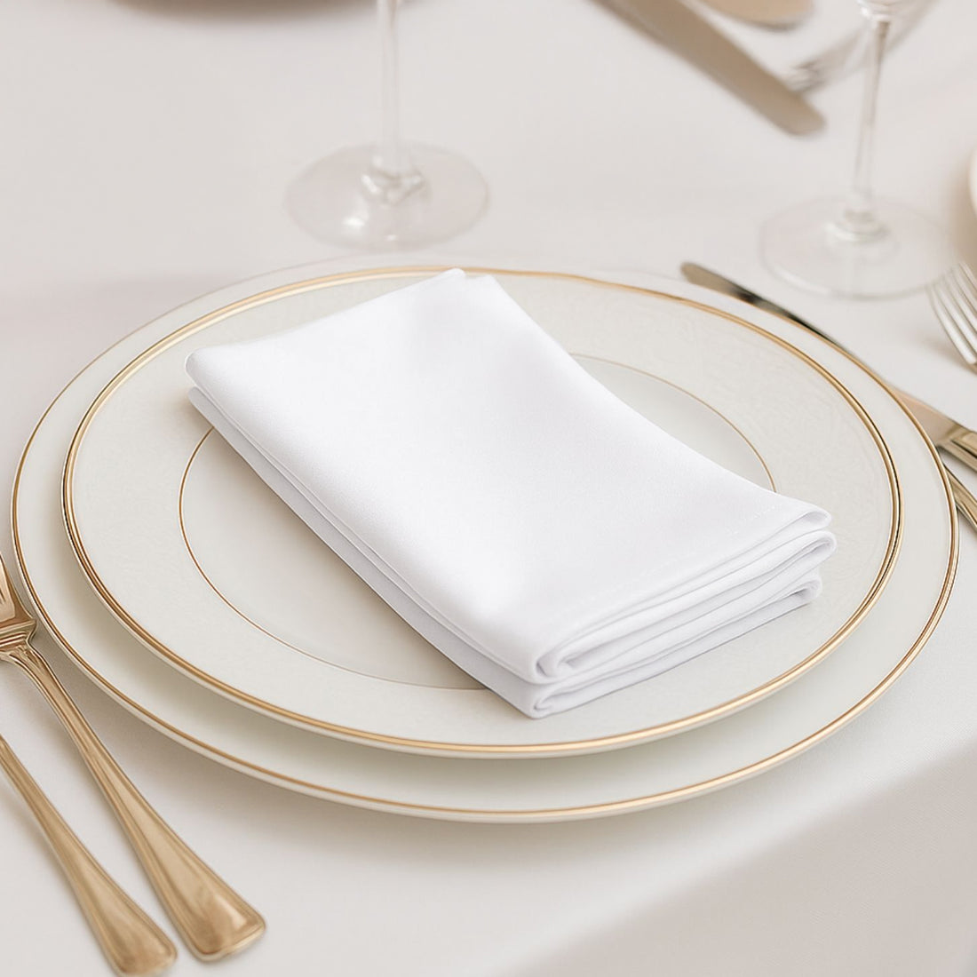 Elegant white napkin folded on a fine china plate with gold accents.