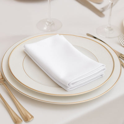 Elegant white napkin folded on a fine china plate with gold accents.
