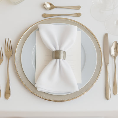 Elegant table setting with a white napkin and silver ring on a blue plate.