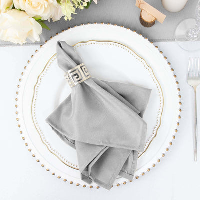 Gray napkin elegantly folded on a decorative plate with floral centerpiece.