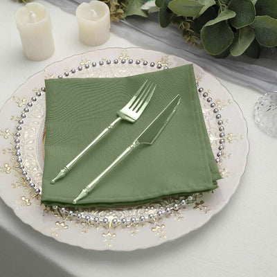 Green napkin with silver fork and knife on an elegant dinner plate.