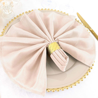 Elegant blush napkin elegantly folded on a decorative plate with gold accents.