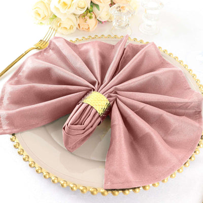 Elegant pink napkin elegantly arranged on a decorative plate with a gold napkin ring.
