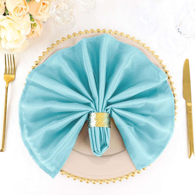 Elegant turquoise napkin elegantly folded on a decorative plate with gold accents.