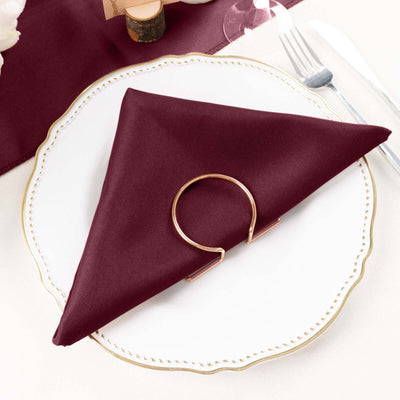 Burgundy napkin elegantly folded on a white plate with a gold ring holder.