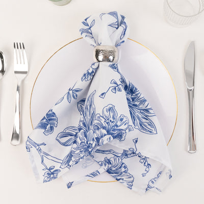 Floral-patterned napkin elegantly arranged on a plate with silver napkin ring.