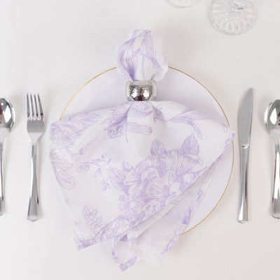Elegant purple floral napkin elegantly arranged on a white plate with silver cutlery.