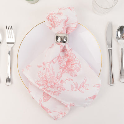 Floral pink napkin elegantly arranged on a white plate with silver cutlery.