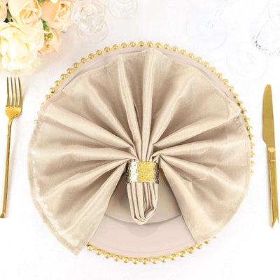 Elegant beige napkin elegantly folded on a decorative plate with gold accents.
