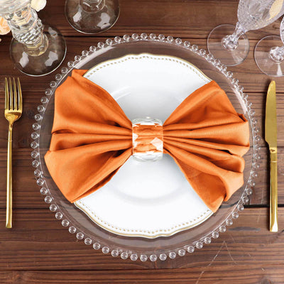 Elegant orange bow tie napkin on a stylish dinner plate setting.