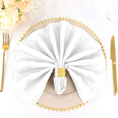 Elegant white napkin on a decorative plate with a gold napkin ring