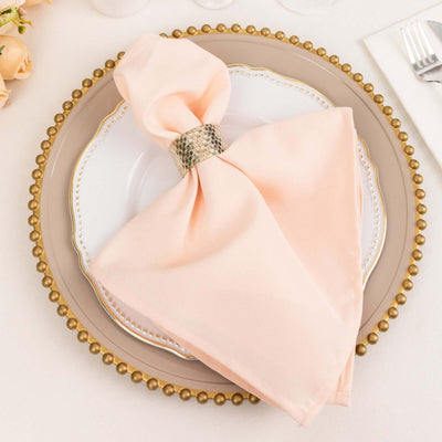 Elegant peach napkin with silver ring on a decorative plate.