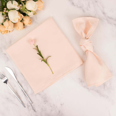 Elegant pink napkin with flower, fork, and knife on marble table.