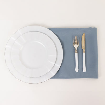 Elegant white dinnerware set on a blue placemat with fork and knife.
