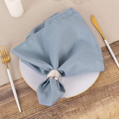 Blue napkin elegantly arranged on a plate with a silver napkin ring.