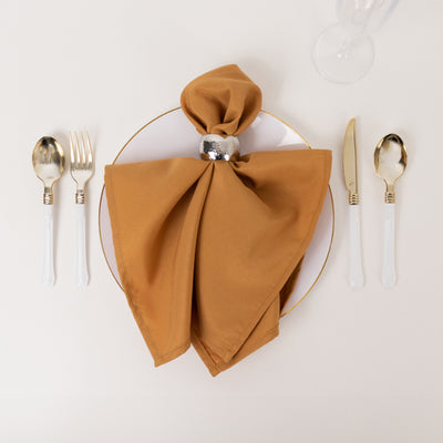 Elegant table setting with a brown napkin, plate, and silver cutlery.