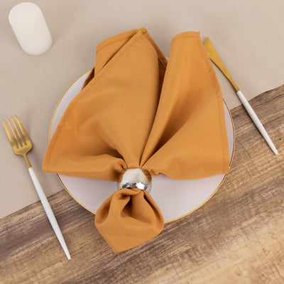 Elegant mustard napkin with silver ring on a white plate.