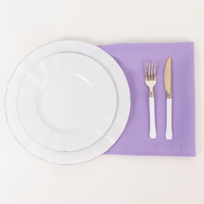 Elegant white dinner plate set on a lavender napkin with gold-accented utensils.