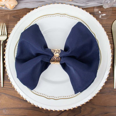 Navy blue napkin tied with a gold napkin ring on an elegant dinner plate.