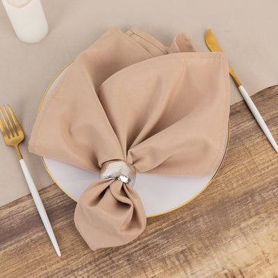 Beige napkin elegantly tied on a plate with a silver napkin ring.