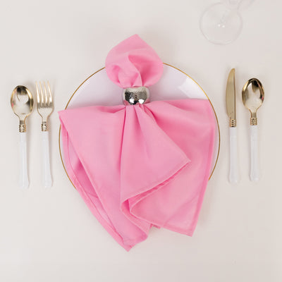 Pink napkin elegantly arranged on a plate with silver cutlery.