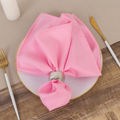 Pink napkin elegantly styled on a plate with a silver napkin ring.