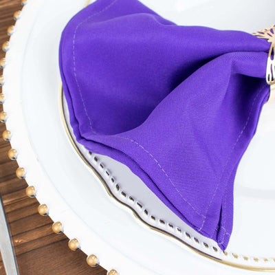 Purple napkin elegantly folded on a decorative plate.