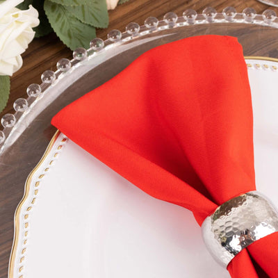 Elegant red napkin with silver ring on a decorative plate.