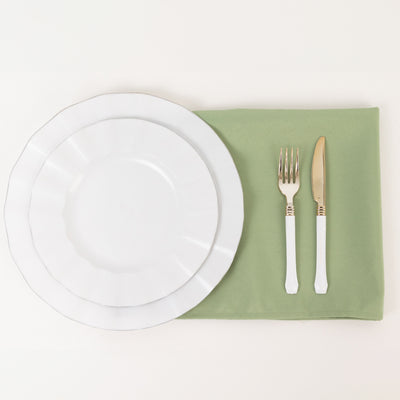 White dinner plates on a green napkin with gold cutlery