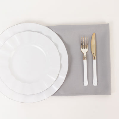 Elegant white dinnerware with gold-accented cutlery on a gray placemat.