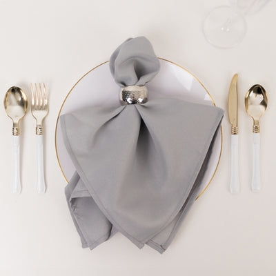 Gray napkin elegantly styled on a white plate with silver cutlery.