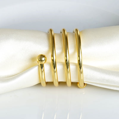 Gold napkin rings set on a white satin napkin.