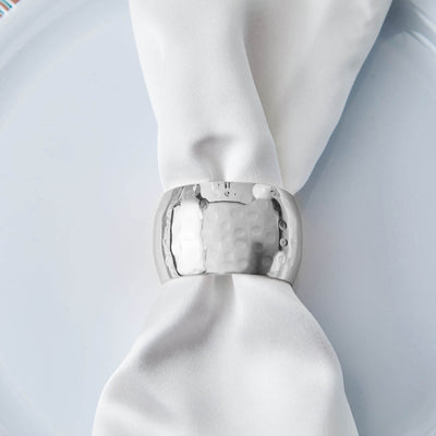 Hammered silver napkin ring on a white napkin and plate.