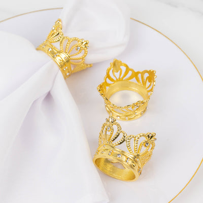 Gold crown napkin rings on a white plate.