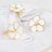 Gold and white flower napkin rings on a white table setting.