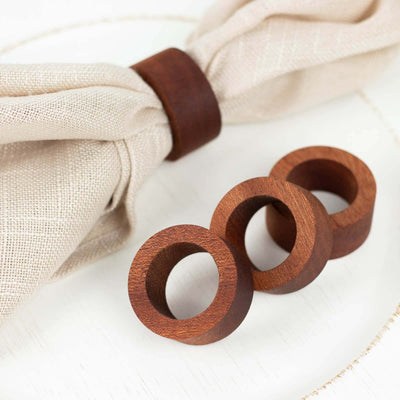 Wooden napkin rings set on a textured napkin.