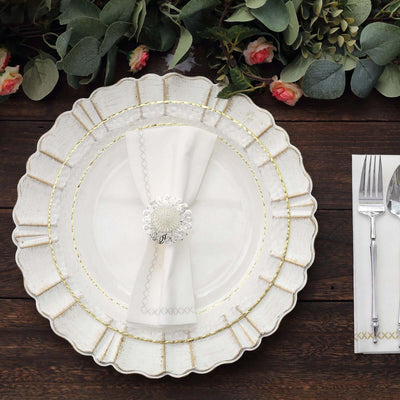 Elegant white plate with gold accents, napkin, and silver napkin holder on wooden table.