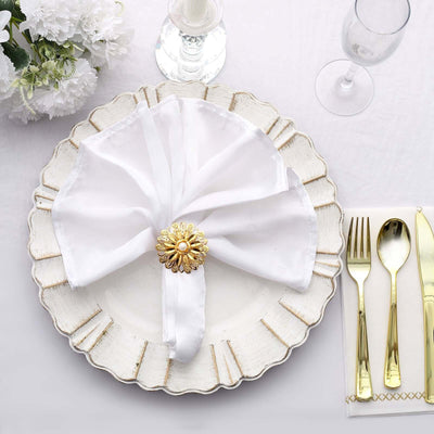 Elegant white napkin with gold holder on a decorative plate, set for dining.