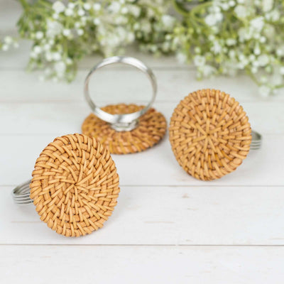 Woven rattan napkin ring holders on a rustic wooden surface.