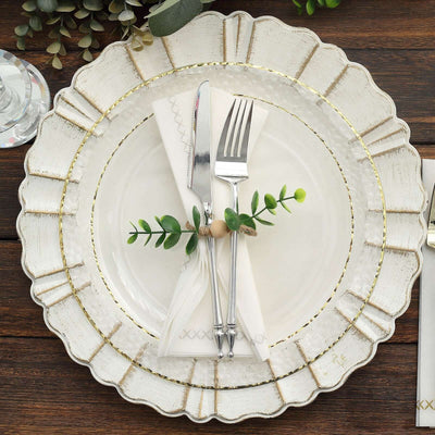 Elegant dinner plate set with silverware and greenery on a rustic wooden table.