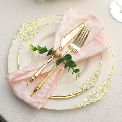 Elegant table setting with gold cutlery on a decorative plate and pink napkin.